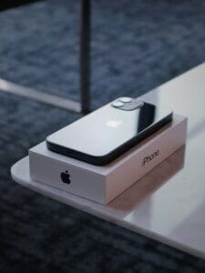 iPhone mini placed on its retail box on a table, showing compact design and flat-edge body.