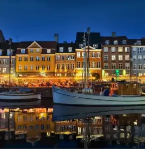 Night-time cityscape with colorful buildings and boats, showcasing Vivo 5G smartphone low-light photography capabilities.