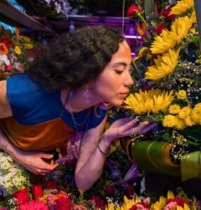 Woman smelling flowers in a colorful flower shop using Google pixel camera